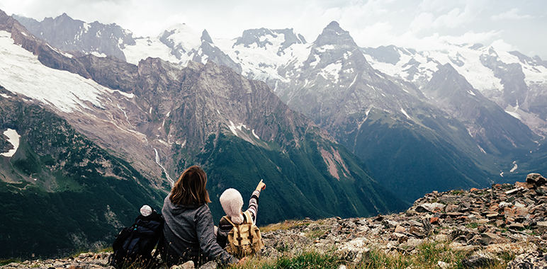 Blog image - adult and child sitting on top of hill looking at mountains in front of them