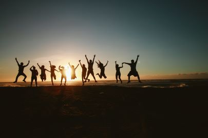 Silhouettes of people jumping with a sunset in the background