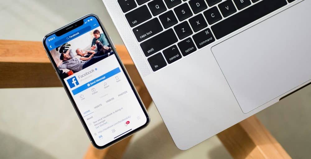 Looking down on a phone with Facebook on the screen and a laptop keyboard